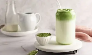 Orzeźwiające matcha z mlekiem kokosowym, z proszkiem matcha na łyżeczce i w miseczce.