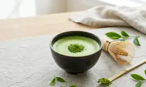 Aksamitna, zielona matcha w ceramicznej miseczce, obok bambusowa miotełka i łyżeczka. Poczuj, jak smakuje matcha.