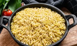 Miseczka pełna złotego makaronu ryżowego orzo, gotowego na pyszne danie.