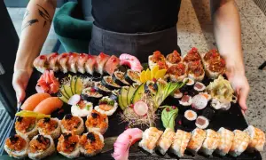 Taca pełna sushi, idealna do nauki, jak jeść sushi. Różne rodzaje rolek, nigiri z łososiem, krewetki i dodatki.
