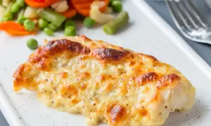 Pyszny, zapieczony filet z dorsza w sosie serowym, podany z kolorowymi warzywami.