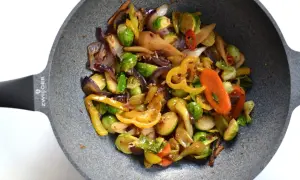 Kolorowe warzywa stir fry z brukselką, papryką i marchewką na patelni.