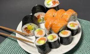 Talerz pełen sushi z łososiem i awokado. Wśród nich rolka z kremowym serkiem do sushi, która dodaje im wyjątkowego smaku.