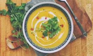Aksamitna tajska zupa z dyni z mlekiem kokosowym, udekorowana kolendrą i chili. Idealna na chłodne dni.
