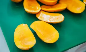 Pokrojone w łódeczki, soczyste mango w ciąży, gotowe do jedzenia, leżą na zielonej desce.