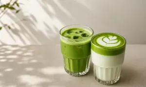 Dwa orzeźwiające matcha latte w szklankach, jedno z pianką i wzorem, drugie z lodem. Idealne na lato, łatwy matcha latte przepis.