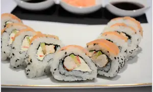 Pyszne rolki sushi z łososiem i kremowym serkiem, w środku widoczne kawałki krewetek do sushi.