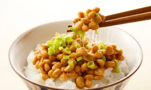 Misternie lepkie ziarna natto, posypane szczypiorkiem, unoszą się nad miską ryżu. To właśnie natto, tradycyjne japońskie danie.