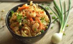 Miseczka pełna krewetek, makaronu ryżowego, kiełków fasoli mung i szczypiorku. To wygląda jak pad thai oryginalny przepis.