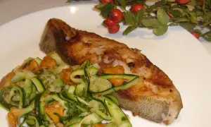 Złocisty halibut stek z chrupiącą skórką, podany z sałatką z cukinii i kurkami.