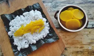 Ryż na nori, a obok miseczka z plasterkami marynowanej rzodkwi.