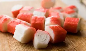Pokrojone paluszki surimi na desce. Idealne do sałatek i przekąsek.