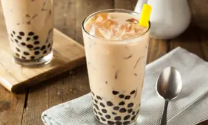 Jak zrobić bubble tea? Pyszny napój z tapioką i lodem w szklance, z żółtą słomką.
