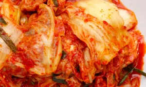 Pikantna kapusta kimchi, z widocznymi liśćmi i przyprawami, gotowa do podania.
