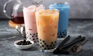 Trzy kolorowe napoje z tapioką, czyli co to jest bubble tea. Różowy, beżowy i niebieski napój z lodem i czarnymi kuleczkami.