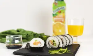 Pyszne sushi z łososiem, ogórkiem i ryżem, podane z sosem sojowym i sokiem pomarańczowym. Idealne na lekki posiłek.