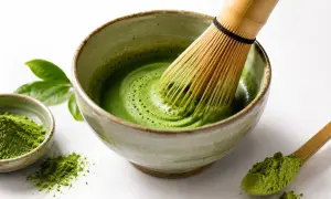 Tradycyjne przygotowanie napoju matcha. Bambusowa miotełka miesza zielony proszek z wodą w miseczce, tworząc piankę.