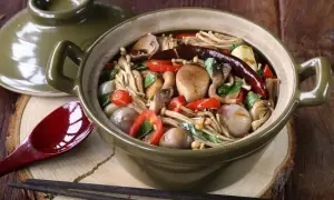 Aromatyczne danie z grzybkami mun, papryczką chili i innymi warzywami w glinianym garnku.