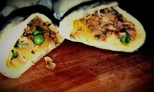 Pyszne bułeczki baozi z soczystym mięsem i groszkiem, przekrojone na pół, prezentują bogactwo nadzienia.