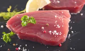 Świeży tuńczyk filet, doprawiony solą i pieprzem, z plasterkiem cytryny i natką pietruszki. Gotowy do grillowania.