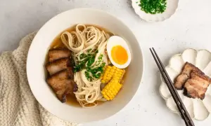 A miseczce shoyu ramen z makaronem, plastrami boczku, jajkiem na pół, kukurydzą i szczypiorkiem.