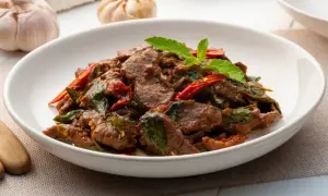 Wołowina po azjatycku z bazylią i papryczką chili, podana w białej misce.