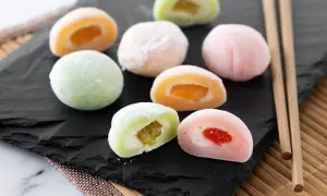 Kolorowe mochi z owocowym nadzieniem, idealne do domowego przepisu na mochi. Patyczki do jedzenia obok.