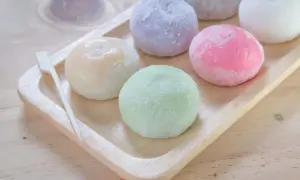 Kolorowe japońskie lody mochi na drewnianej tacy, wyglądają jak małe, słodkie kuleczki.