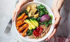 Zdrowy bowl z kaszą gryczaną, pieczonymi batatami, awokado, tofu, jarmużem i czerwoną cebulą.