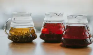 Trzy szklane dzbanki z naparami. Jeden z zieloną herbatą, bogatą w katechiny, dwa z czerwonymi napojami.