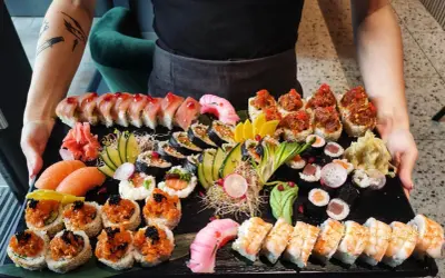 Taca pełna sushi, idealna do nauki, jak jeść sushi. Różne rodzaje rolek, nigiri z łososiem, krewetki i dodatki.