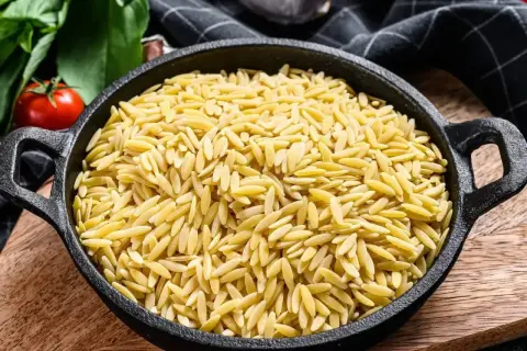 Miseczka pełna złotego makaronu ryżowego orzo, gotowego na pyszne danie.