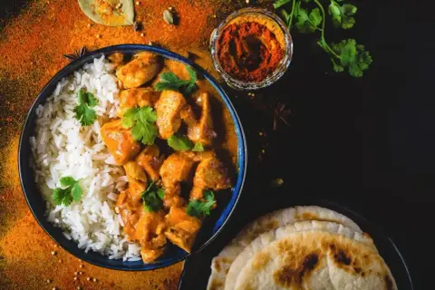 Aksamitny butter chicken, przepis oryginalny, podany z ryżem i chlebkiem naan. Aromatyczne przyprawy dopełniają danie.