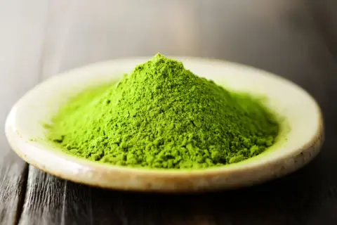 Góra zielonego proszku matcha na talerzyku. Czy matcha pobudza? Ten intensywny kolor sugeruje, że tak!