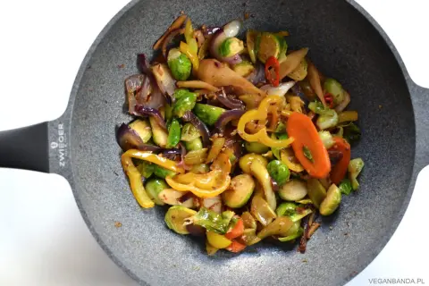 Kolorowe warzywa stir fry z brukselką, papryką i marchewką na patelni.