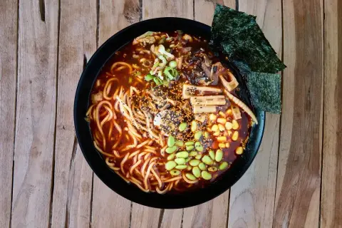 Miseczka aromatycznego ramen z makaronem, edamame, kukurydzą, grzybami i nori. Pyszny posiłek, który może mieć różną liczbę ramen kcal.