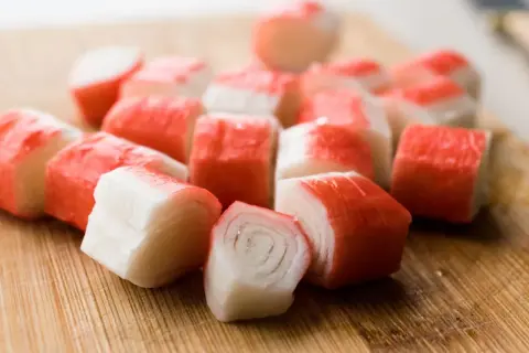 Pokrojone paluszki surimi na desce. Idealne do sałatek i przekąsek.
