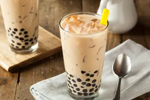 Jak zrobić bubble tea? Pyszny napój z tapioką i lodem w szklance, z żółtą słomką.