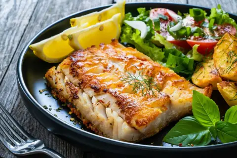 Złocista dorada wędzona, podana z pieczonymi ziemniakami, świeżą sałatką i cytryną. Pyszne danie rybne.