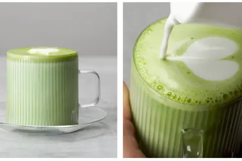 Zielone matcha z mlekiem w szklance z uchwytem, z pianką w kształcie serca.