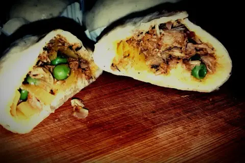 Pyszne bułeczki baozi z soczystym mięsem i groszkiem, przekrojone na pół, prezentują bogactwo nadzienia.