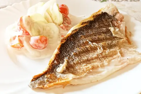 Dorada grillowana z chrupiącą skórką, podana z orzeźwiającą sałatką z pomidorków i ogórka w sosie.