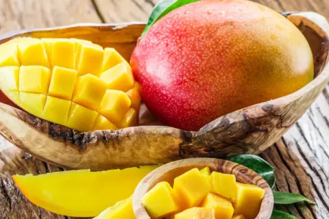 Słodkie, soczyste mango w drewnianej misce. Idealne na codzienne jedzenie mango, pełne witamin i słońca.