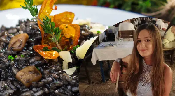 Pyszne risotto z **atramentem kałamarnicy**, ozdobione ziołami i pomidorkami, obok uśmiechniętej kobiety siedzącej w restauracji.