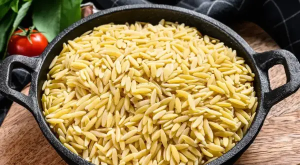 Miseczka pełna złotego makaronu ryżowego orzo, gotowego na pyszne danie.