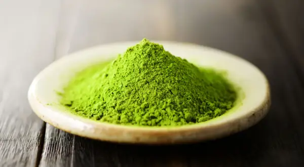Góra zielonego proszku matcha na talerzyku. Czy matcha pobudza? Ten intensywny kolor sugeruje, że tak!