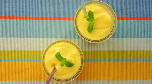 Dwa pyszne mango lassi, orzeźwiające napoje z Indii, ozdobione listkami mięty, czekają na spróbowanie.