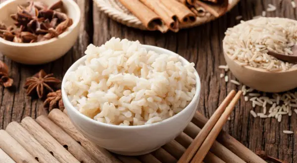 Miseczka parującego congee, obok miseczki z ryżem, anyżem i laskami cynamonu.