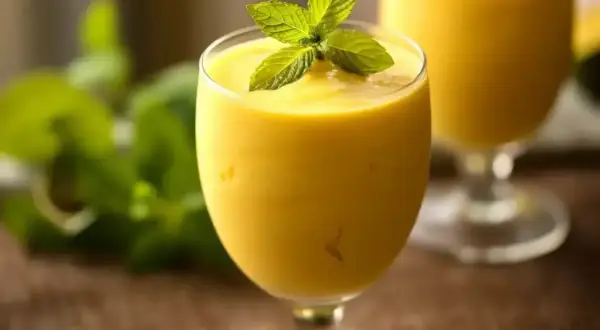 Orzeźwiający mango lassi z pulpy, udekorowany listkami mięty. Idealny na upalne dni.
