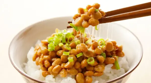 Misternie lepkie ziarna natto, posypane szczypiorkiem, unoszą się nad miską ryżu. To właśnie natto, tradycyjne japońskie danie.